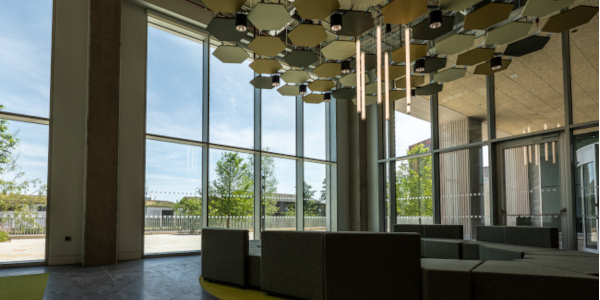 a large round sofa situated in the middle of an industrial looking room that has large glass windows.