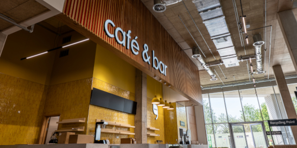 A cafe counter in an industrial space with a cheerful yellow interior.