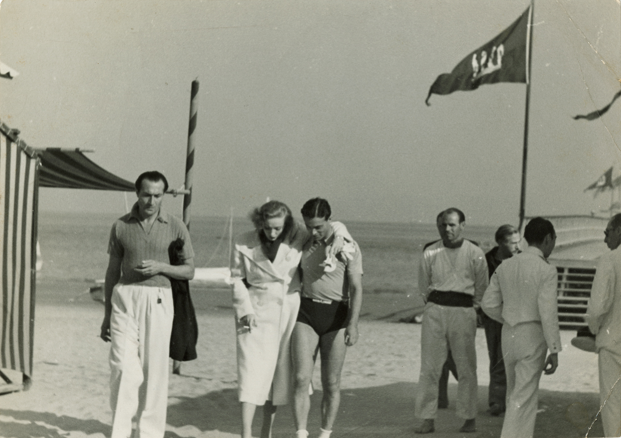 A photograph of Oliver Messel and Marlene Dietrich on a beach with a few people around them