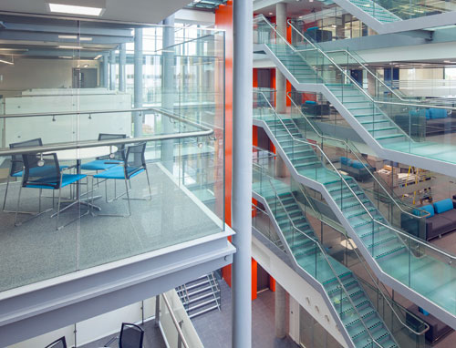 A multistory atrium with glass walls and visible seating areas and meeting rooms.