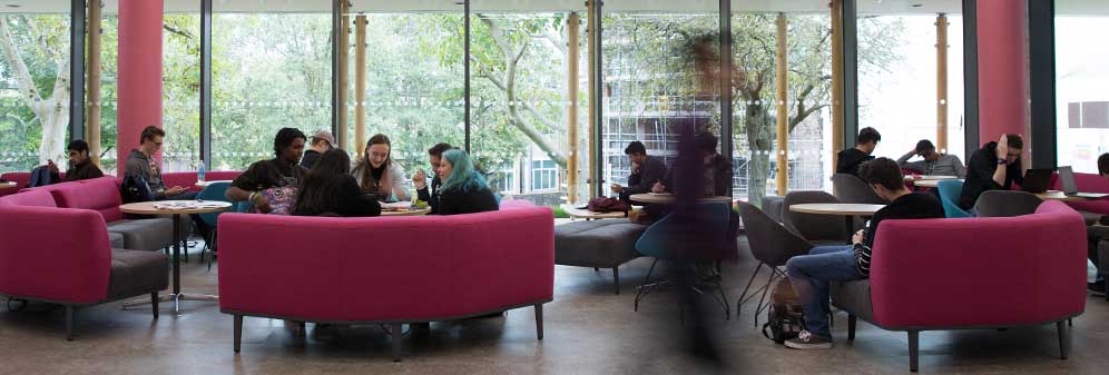 People sit, talking on sofas in the atrium.