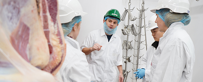 students wearing ppe in abattoir chiller