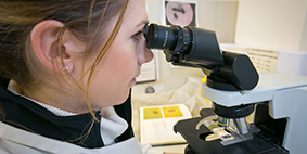 person looking down a microscope